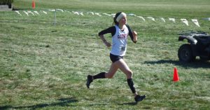Senior Sarah Goodrich running at a cross country meet.